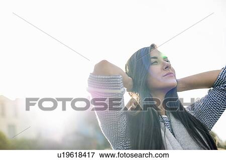 Young woman with hands behind head in sunlight View Large Photo Image Stock Photo - Young woman with hands behind head in sunlight. Fotosearch