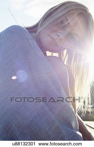 Stock Image - Young woman wrapped in a blanket in sunshine. Fotosearch