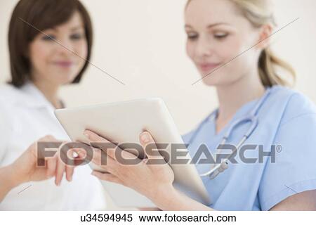 Doctors using a tablet computer View Large Photo Image Stock Photography - Doctors using a tablet computer. Fotosearch