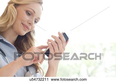 Stock Image - Nurse using a smart phone. Fotosearch