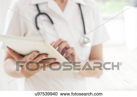 Stock Image - Nurse using a tablet computer. Fotosearch