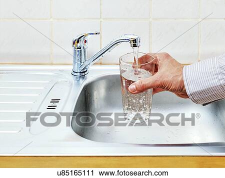 Stock Image - Pouring glass of tap water. Fotosearch