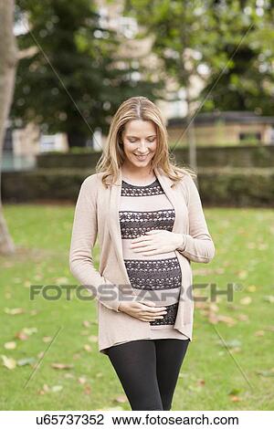 Stock Image - Pregnant woman in park. Fotosearch