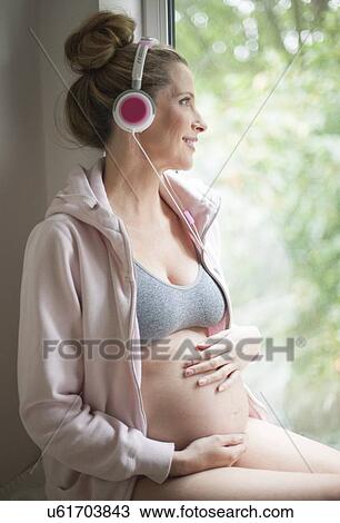Stock Image - Pregnant woman listening to music. Fotosearch