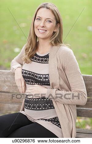 Stock Photograph - Pregnant woman sitting in park. Fotosearch