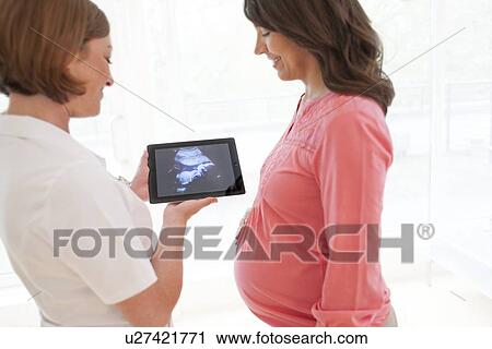 Stock Image - Pregnant woman with baby scan. Fotosearch