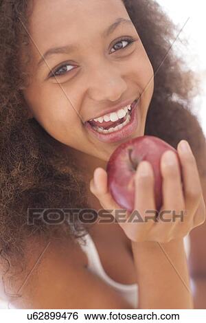 Teenage girl eating an apple View Large Photo Image Stock Photograph - Teenage girl eating an apple. Fotosearch
