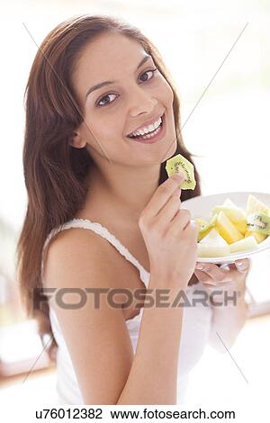 Stock Image - Woman eating fruit. Fotosearch