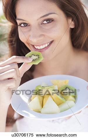 Stock Photography - Woman eating fruit. Fotosearch