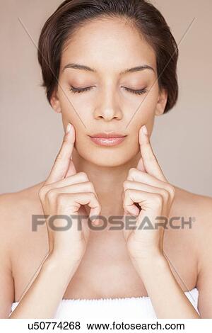 Woman massaging her face View Large Photo Image Stock Photo - Woman massaging her face. Fotosearch