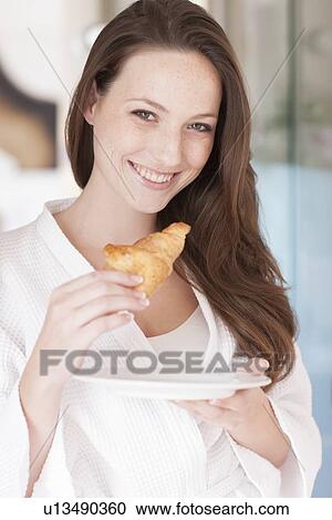 Stock Image - Young woman eating a pastry. Fotosearch