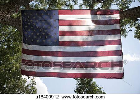 Stock Image - Sun is seen through backlighted American Flag, Ridgeway, CO. Fotosearch