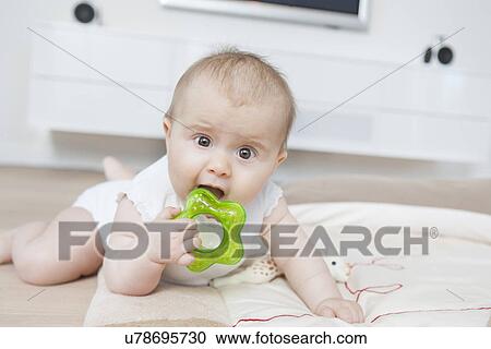 Stock Image - Baby biting teething ring. Fotosearch