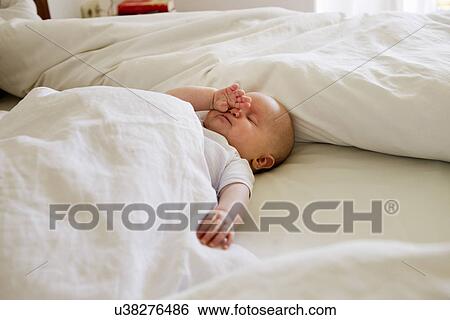 Stock Photograph - Baby girl asleep on bed. Fotosearch