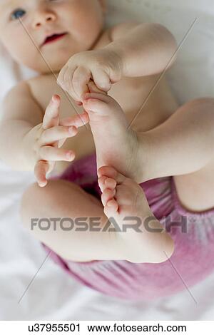 Stock Image - Baby girl playing with feet. Fotosearch