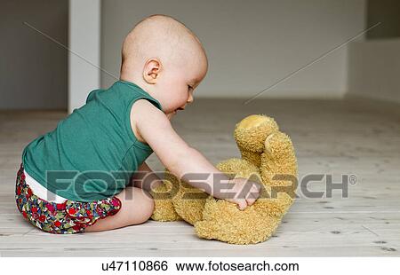 Baby girl playing with teddy bear on floor View Large Photo Image Stock Photograph - Baby girl playing with teddy bear on floor. Fotosearch