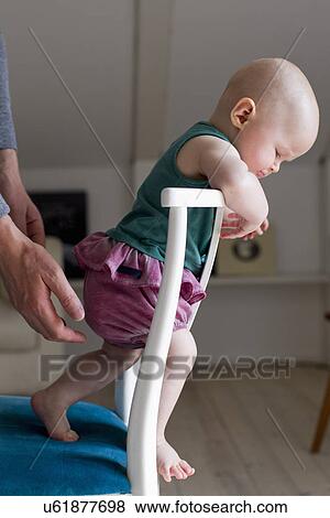 Baby girl standing on chair View Large Photo Image Stock Photo - Baby girl standing on chair. Fotosearch