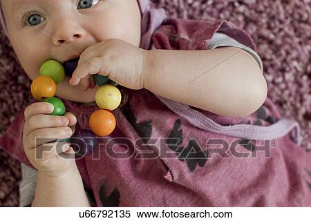 Stock Photography - Baby girl with teething toy. Fotosearch
