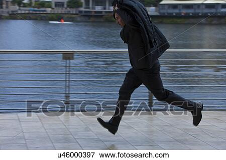Businessman running to shelter from rain View Large Photo Image Stock Photo - Businessman running to shelter from rain. Fotosearch