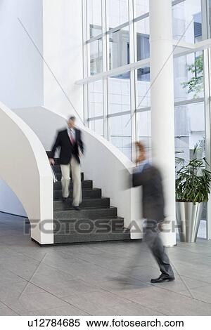 Businessmen on the move in office atrium View Large Photo Image Stock Photography - Businessmen on the move in office atrium. Fotosearch