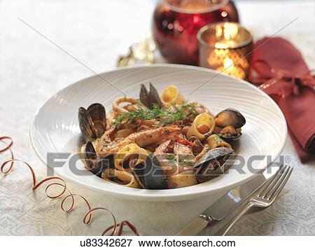 Calamarata seafood pasta with fresh mussels, king prawns, calamari, garlic, chillies, basil leaves, dill, white wine and tomato sauce among festive decorations View Large Photo Image Stock Photo - Calamarata seafood pasta with fresh mussels, king prawns, calamari, garlic, chillies, basil leaves, dill, white wine and tomato sauce among festive decorations. Fotosearch