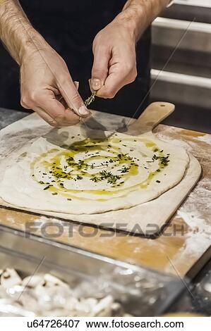 Stock Photo - Chef preparing pizza bread in commercial kitchen. Fotosearch