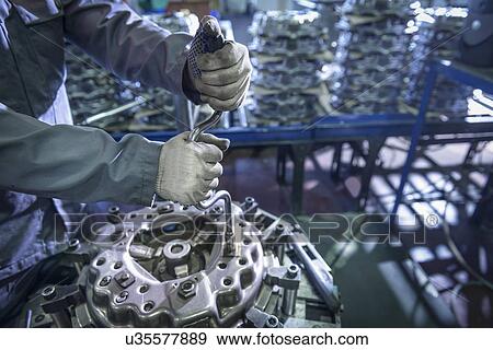 Stock Photo - Close up of engineer assembling industrial clutch on production line. Fotosearch