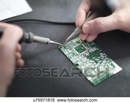 Stock Photo - Close up of engineer soldering prototype circuit board. Fotosearch
