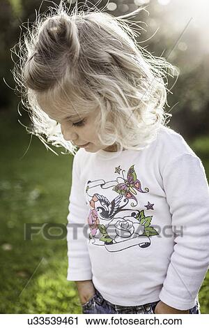 Stock Image - Close up of female toddler with hands in pockets. Fotosearch