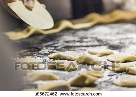 Stock Image - Close up of hand shaping tortellini in kitchen. Fotosearch
