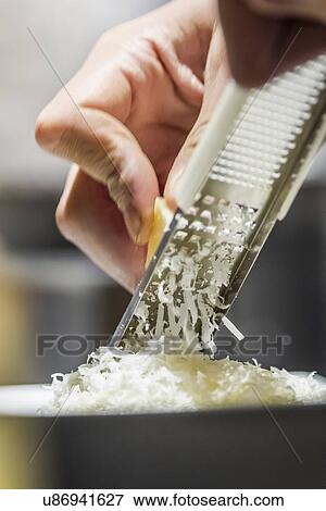 Stock Photo - Close up of male hand grating parmesan cheese. Fotosearch