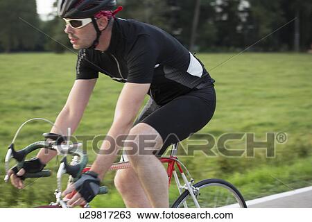 Stock Image - Close up of mature male cycling on country road. Fotosearch