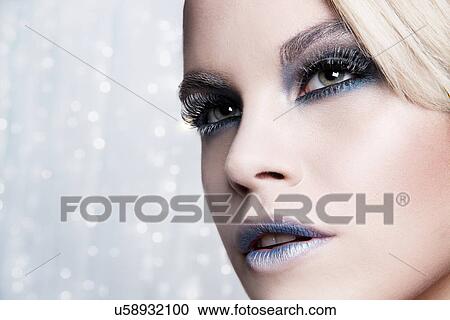 Stock Image - Close up of woman against glittery background. Fotosearch
