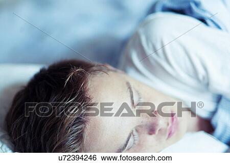 Stock Photograph - Close up of young man asleep in bed. Fotosearch