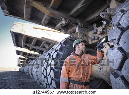 Coal miner inspects dumper truck tyre tread in surface coal mine View Large Photo Image Stock Photo - Coal miner inspects dumper truck tyre tread in surface coal mine. Fotosearch