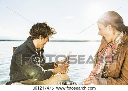 Couple by lake opening champagne View Large Photo Image Stock Photography - Couple by lake opening champagne. Fotosearch