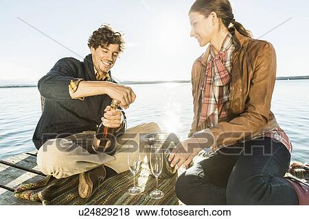 Stock Photo - Couple by lake with wine. Fotosearch