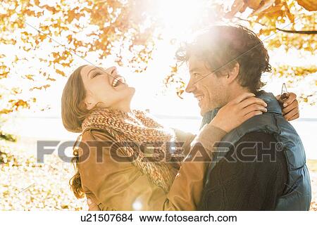 Picture - Couple hugging by tree in sunlight. Fotosearch