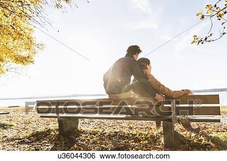 Stock Photograph - Couple sitting on bench, rear view. Fotosearch