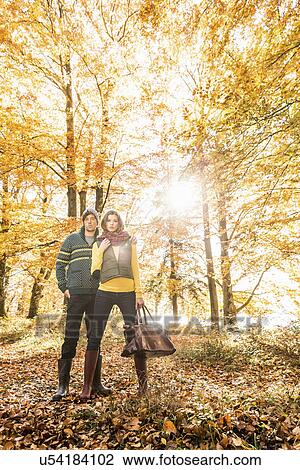 Stock Image - Couple standing in forest in autumn. Fotosearch