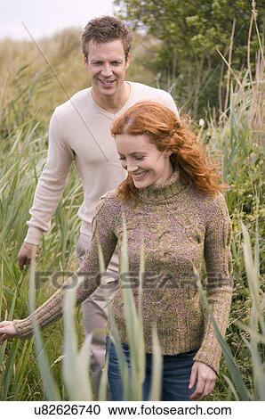 Couple strolling on grassy field View Large Photo Image Stock Image - Couple strolling on grassy field. Fotosearch