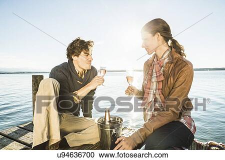 Stock Image - Couple toasting with champagne, Lake Starnberg, Bavaria, Germany. Fotosearch