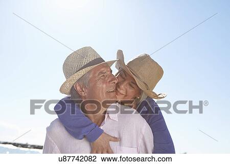 Stock Image - Couple wearing straw hats on beach. Fotosearch