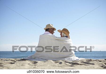 Stock Image - Couple wearing straw hats on beach. Fotosearch