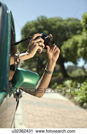 Cropped image of young woman photographing from car window View Large Photo Image Stock Image - Cropped image of young woman photographing from car window. Fotosearch