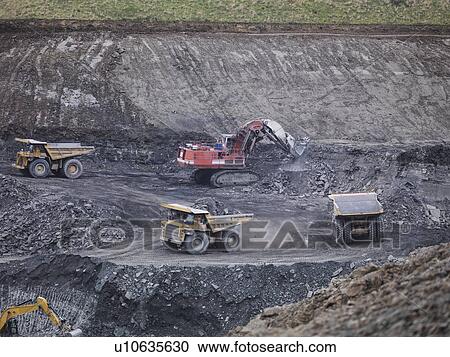 Stock Image - Diggers and dumper trucks at work in surface coal mine. Fotosearch