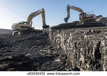 Stock Image - Diggers working on coal seam in surface coal mine. Fotosearch