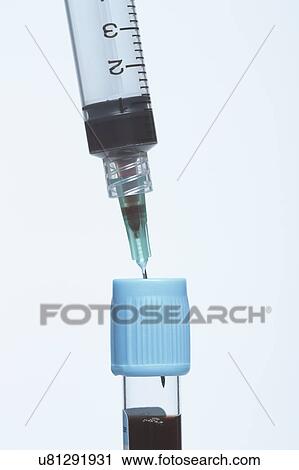 Stock Image - Disposable plastic medical syringe inserted into blue blood tube containing synthetic blood sample.. Fotosearch