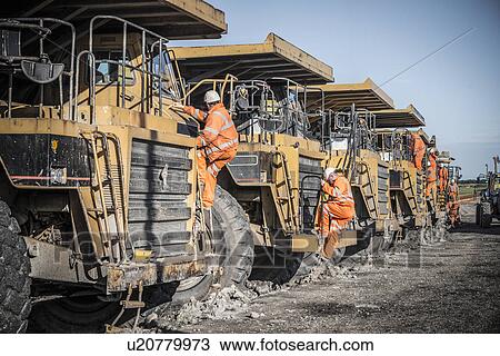 Stock Image - Dumper truck drivers climb down for break at surface coal mine. Fotosearch