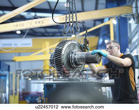 Stock Image - Engineer assembling industrial gearbox in engineering factory. Fotosearch
